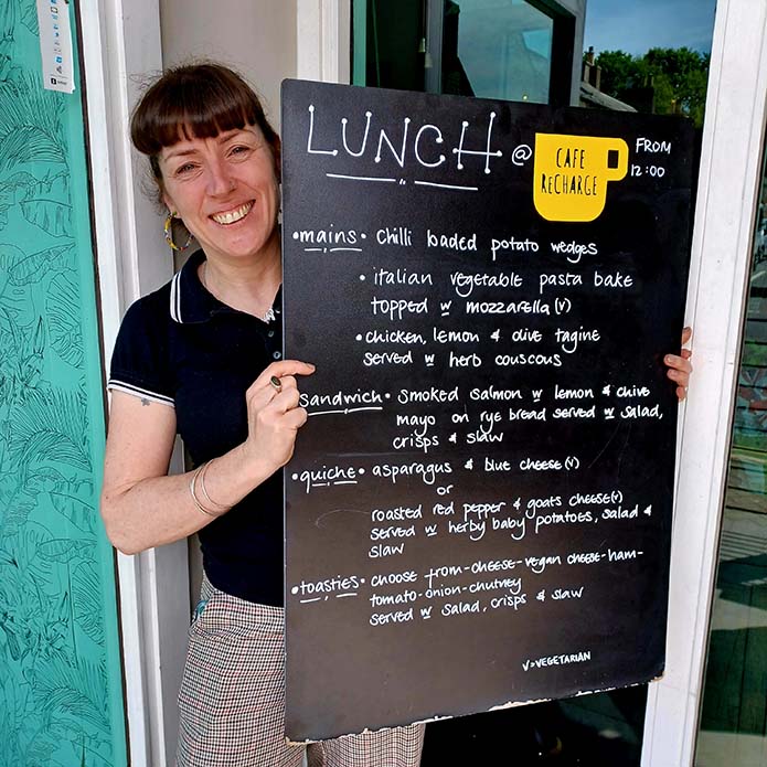 a staff member holding up the daily menu at cafe recharge in galashiels